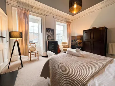 a bedroom with a bed and a lamp and windows at Garnethill Charm 3 Bed Flat Central Glasgow in Glasgow