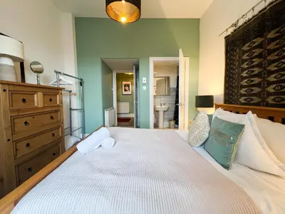 a bedroom with a large white bed and a bathroom at Garnethill Charm 3 Bed Flat Central Glasgow in Glasgow
