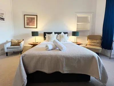 a bedroom with a large bed with two chairs at Garnethill Charm 3 Bed Flat Central Glasgow in Glasgow