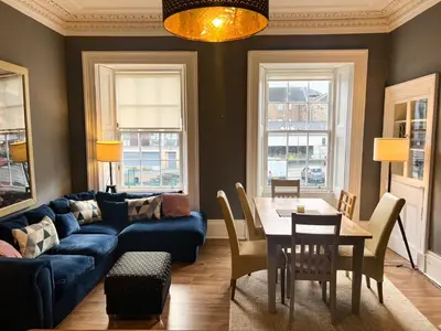 a living room with a blue couch and a table at Garnethill Charm 3 Bed Flat Central Glasgow in Glasgow