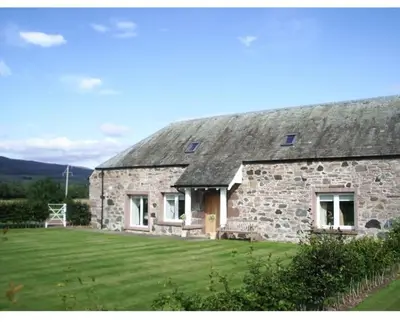 a stone house with a grassy yard in front of it at Fairness Cottage, Near Comrie in Comrie