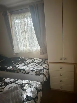 a bedroom with a bed and a dresser and a window at Bay 1 in Kirkcolm