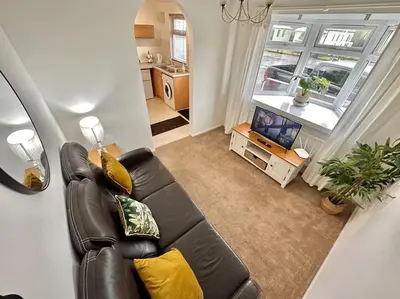 a living room with a leather couch and a television at Semi-detached 1-Bedroom Chalet at Maryville Caravan Site - Uddingston, Glasgow in Uddingston