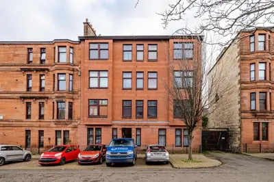 a group of cars parked in a parking lot in front of a building at Stunning Ground Floor flat in Southside. in Glasgow
