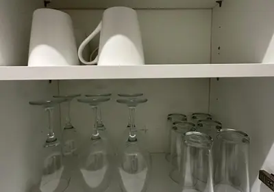 a white shelf with wine glasses and wine bottles at Trendy West End Apartment, Glasgow in Glasgow
