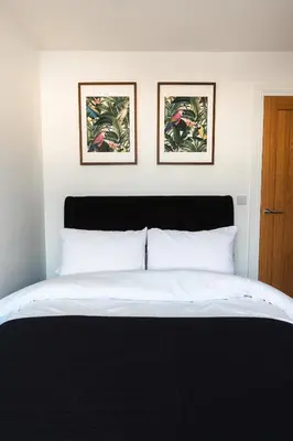 a bedroom with a bed with two pictures on the wall at Barnet House Serviced Apartments in Dunfermline