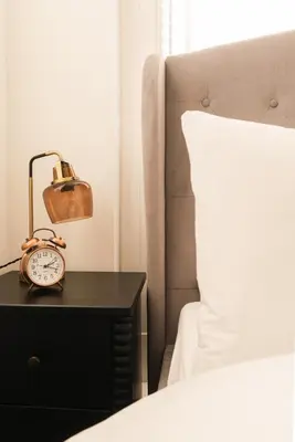 a alarm clock on a nightstand next to a bed at Barnet House Serviced Apartments in Dunfermline