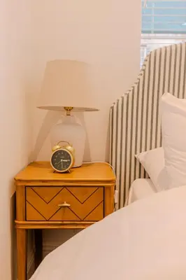 a bedside table with a lamp and a clock on it at Barnet House Serviced Apartments in Dunfermline
