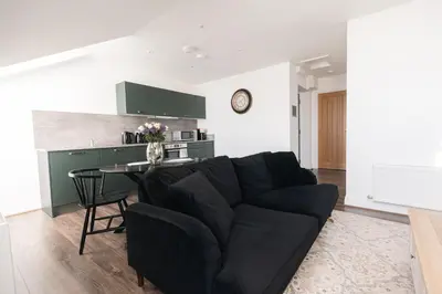 a living room with a black couch and a table at Barnet House Serviced Apartments in Dunfermline