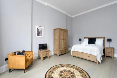 a bedroom with a bed and a chair and a television at Modern George Street Studio sleeping 2 in Edinburgh