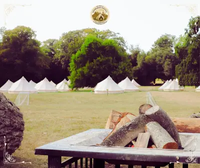 a table with a pile of logs and white tents at Edinburgh Festival Glamping By Stay Social Stays in Edinburgh
