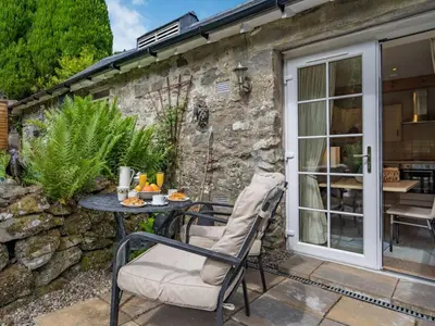 a patio with a table and chairs and a stone wall at 1 Bed in Callander oc-pe173 in Strathyre