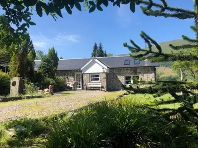 an exterior view of a stone house with a yard at 1 Bed in Callander oc-pe173 in Strathyre