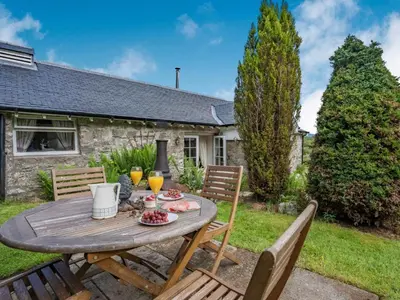 a wooden table and chairs in the backyard of a house at 1 Bed in Callander oc-pe173 in Strathyre