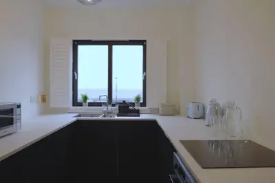 a white kitchen with a sink and a window at Seaside Apartment in Largs