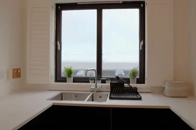 a kitchen with a sink and a large window at Seaside Apartment in Largs