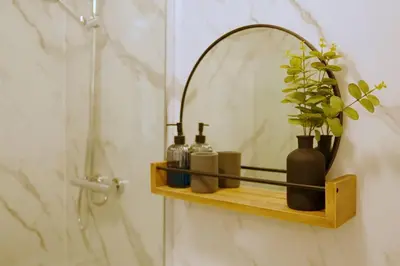 a bathroom with a shelf with bottles and a mirror at Seaside Apartment in Largs