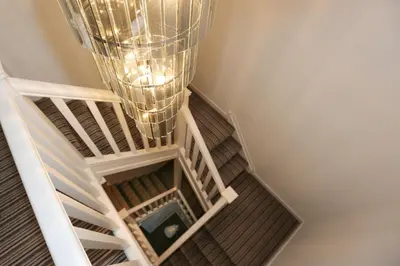 a staircase with a chandelier hanging from the ceiling at Viewpoint Villa - Luxury 4 Bedroom villa with elevated views in Rothesay