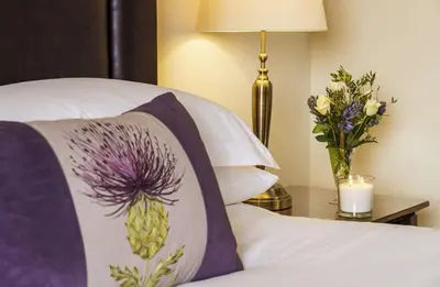 a bed with a pillow and a vase of flowers at Macdonald Inchyra Hotel & Spa in Falkirk