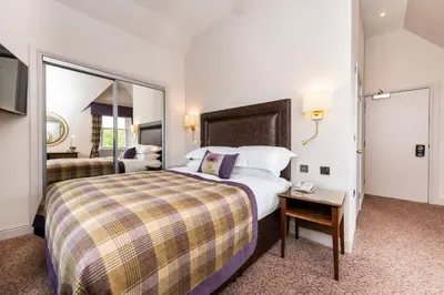 a hotel room with a large bed and a mirror at Macdonald Inchyra Hotel & Spa in Falkirk