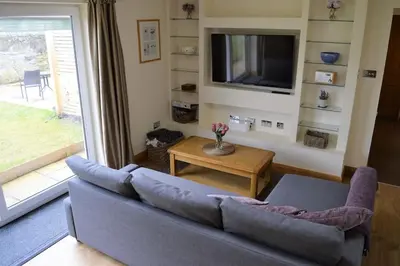 a living room with a blue couch and a tv at Wardie Garden Cottage in Edinburgh
