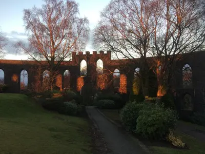 an old brick building with trees and a path at Failte Bed & Breakfast in Oban