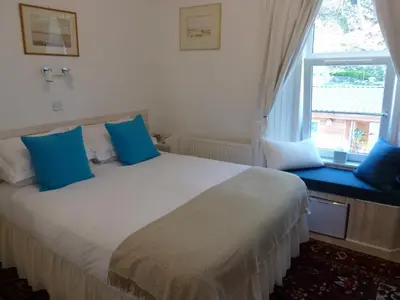 a bedroom with a large bed with blue pillows and a window at Failte Bed & Breakfast in Oban