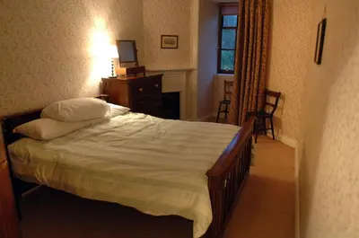 a bedroom with a bed and a dresser and a window at Butlers Quarters Apartment in Cairndow