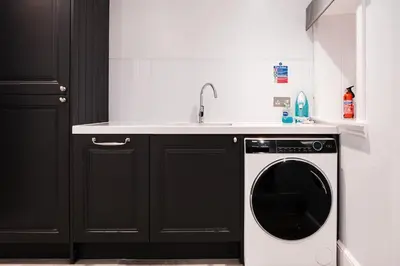 a kitchen with a washing machine and a sink at The Old School House, luxury home with hot tub. in Minnigaff