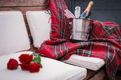a table with a blanket and a bottle of wine and roses at The Old School House, luxury home with hot tub. in Minnigaff