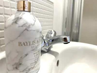 a bottle of soap sitting on top of a bathroom sink at Private room with en-suite and parking in shared flat in Glasgow