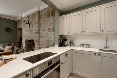 a kitchen with white cabinets and a stone wall at Rose Apartment in Edinburgh