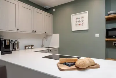 a kitchen with white cabinets and a counter with a loaf of bread at Rose Apartment in Edinburgh