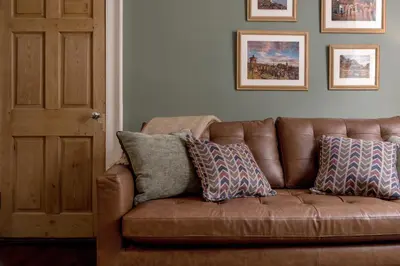 a brown leather couch with pillows in a living room at Rose Apartment in Edinburgh