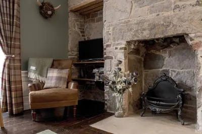 a living room with a stone fireplace with a chair and a television at Rose Apartment in Edinburgh