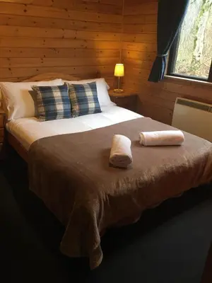 a bedroom with a bed with two towels on it at Loch Lomond Lodge in Rowardennan