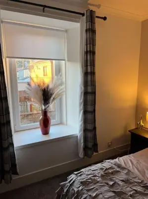 a bedroom with a window with a vase with flowers in it at Newly refurbished flat - Callander in Callander