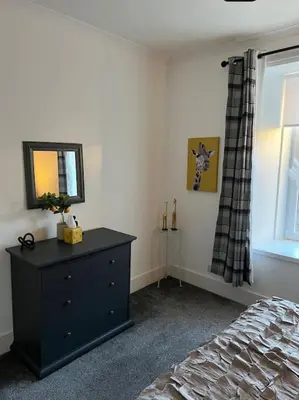 a bedroom with a dresser and a mirror and a bed at Newly refurbished flat - Callander in Callander