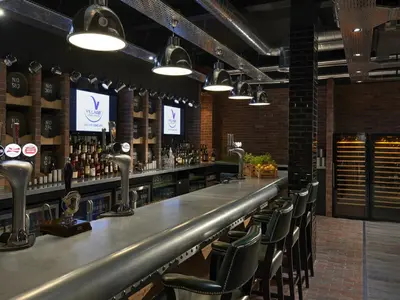 a bar with chairs and a counter with alcohol at Village Hotel Edinburgh in Edinburgh