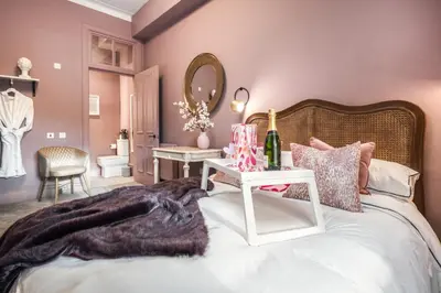 a bedroom with a bed with a table and a mirror at Boutique Home Stay Blossom in Paisley