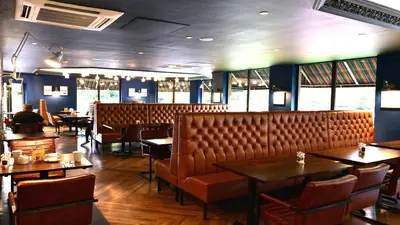a restaurant with tables and chairs and a leather bench at Holiday Inn Glasgow - East Kilbride by IHG in East Kilbride