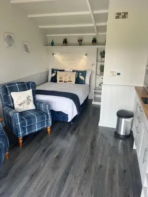 a bedroom with a bed and a couch and a chair at Capledrae Farmstay Shepherds Huts in Cardenden