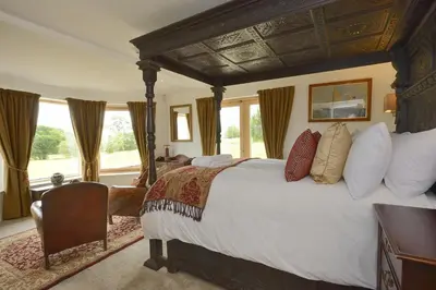 a bedroom with a large bed in a room with windows at The Lodge at Carrick Castle Estate in Cairndow