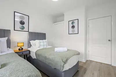 a white bedroom with two beds and a door at Welcoming Home in Johnstone, Near Glasgow Airport - Bonnie Lodgings in Johnstone