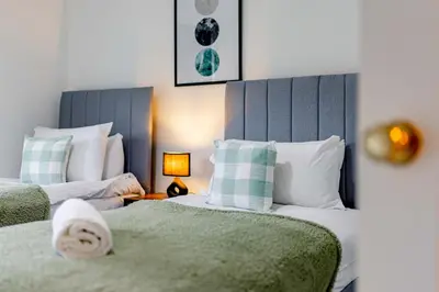 a bedroom with two beds and a lamp on a table at Welcoming Home in Johnstone, Near Glasgow Airport - Bonnie Lodgings in Johnstone