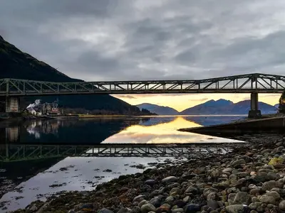 a bridge over a body of water with mountains in the background at Roe Deer Cottage in North Ballachulish