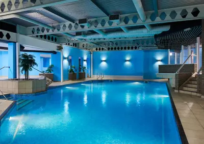 a large swimming pool in a building with blue walls at Leonardo Edinburgh Murrayfield in Edinburgh
