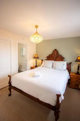 a bedroom with a large white bed and a chandelier at Harvest House with Games Room in Stirling