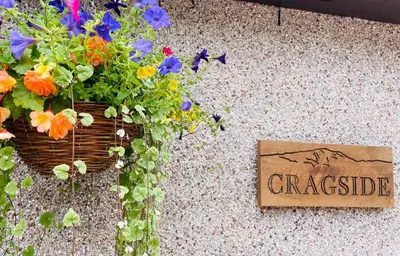 a sign sitting on the ground next to a basket of flowers at Cragside in Callander