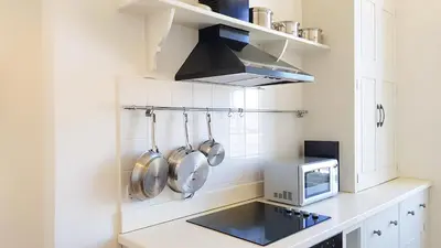 a kitchen with white cabinets and a microwave at Spacious 2-Bedroom Georgian Edinburgh City Apartment in Edinburgh